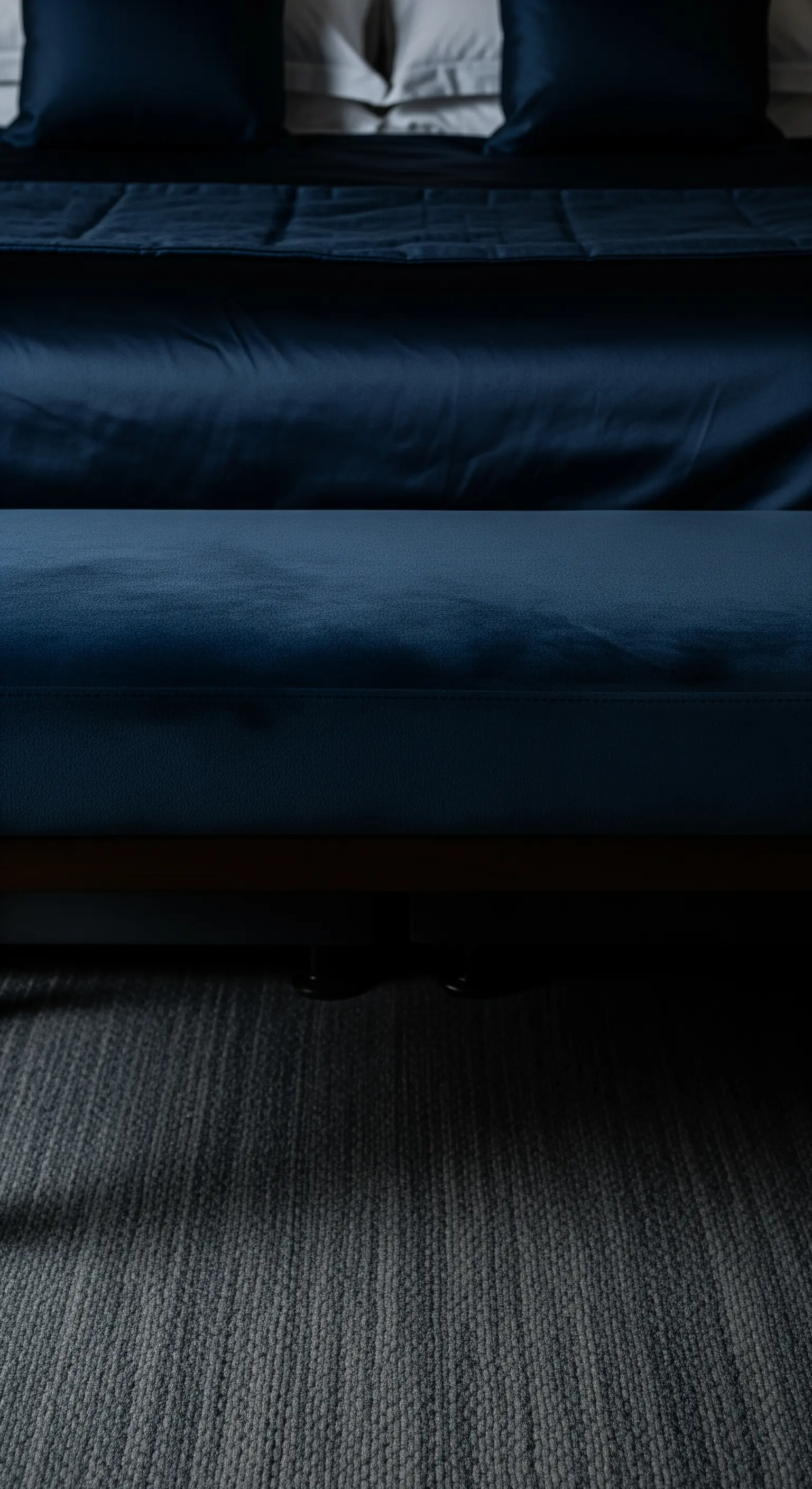 Nachtblaue Samtbank am Bettende auf grauem Teppich