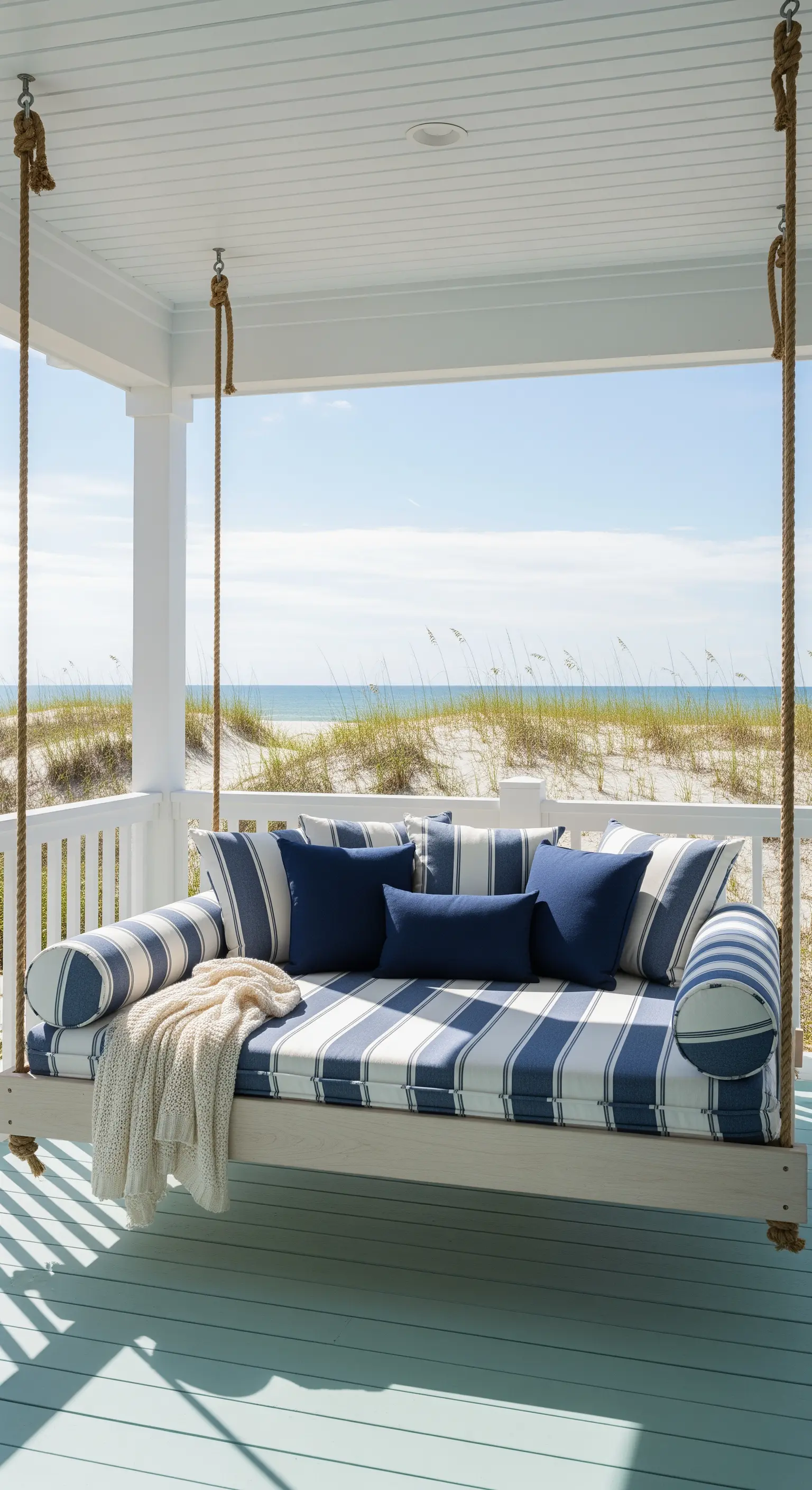 Schaukelsofa auf der Veranda mit blau-weiß gestreiften Kissen und Meerblick