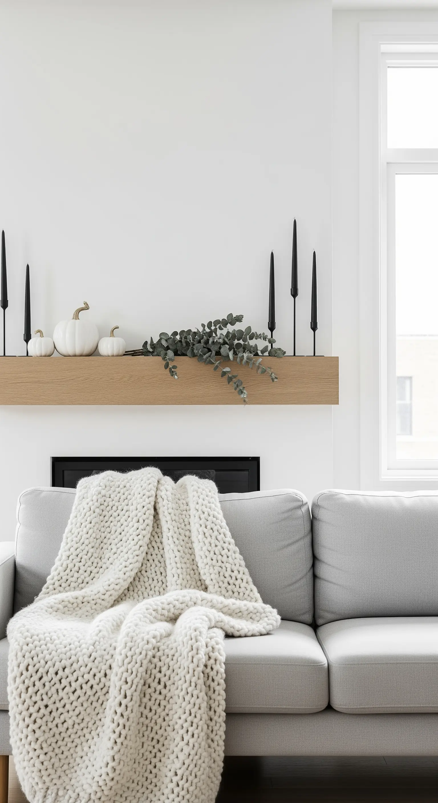 Mantel mit weißen Kürbissen, schwarzen Kerzen und Eukalyptus in Scandi-Stil.