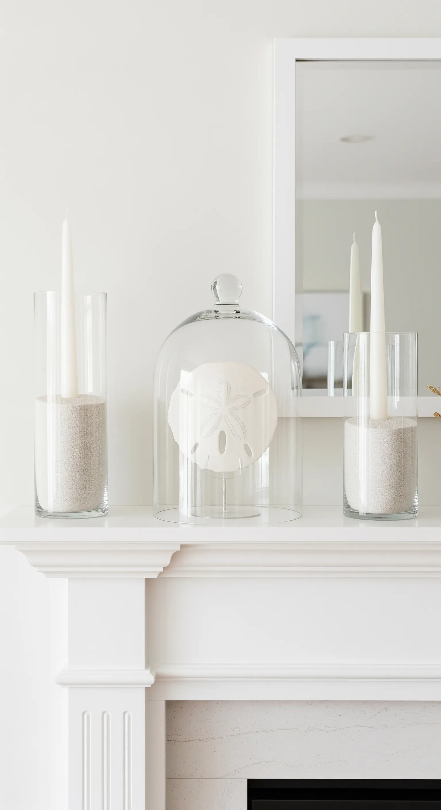 Elegante weiße Kaminumrandung mit Seeigel-Deko unter einer Glasglocke.