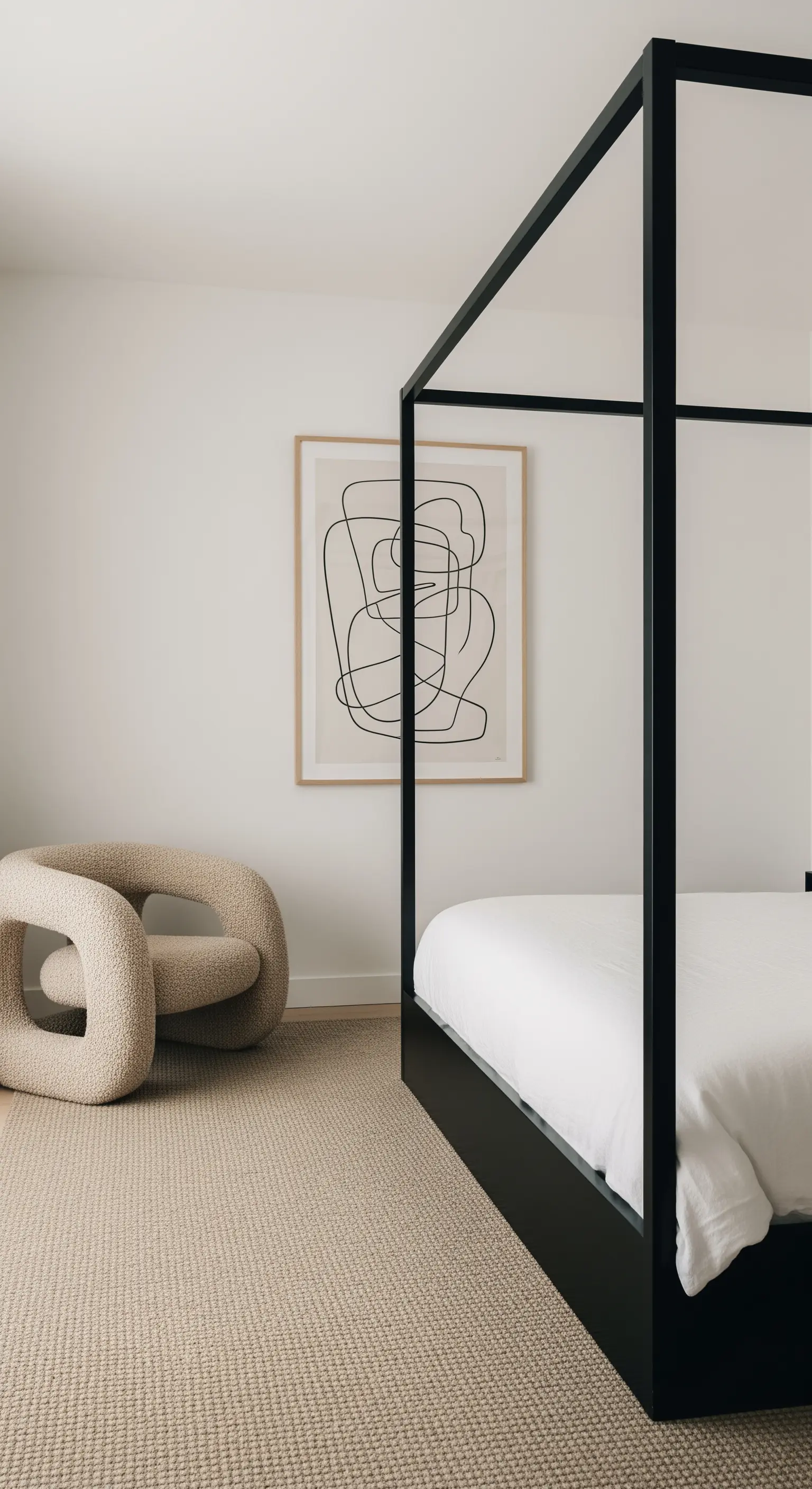 Minimalistisches Schlafzimmer mit einem schwarzen, geradlinigen Himmelbett und einem skulpturalen Sessel