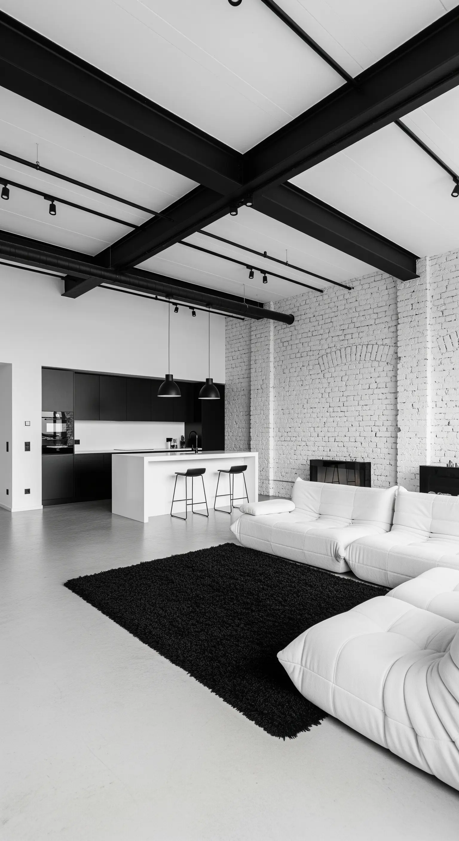 Offenes Loft mit weißer Backsteinwand und einem schwarzen Hochflorteppich als Akzent.