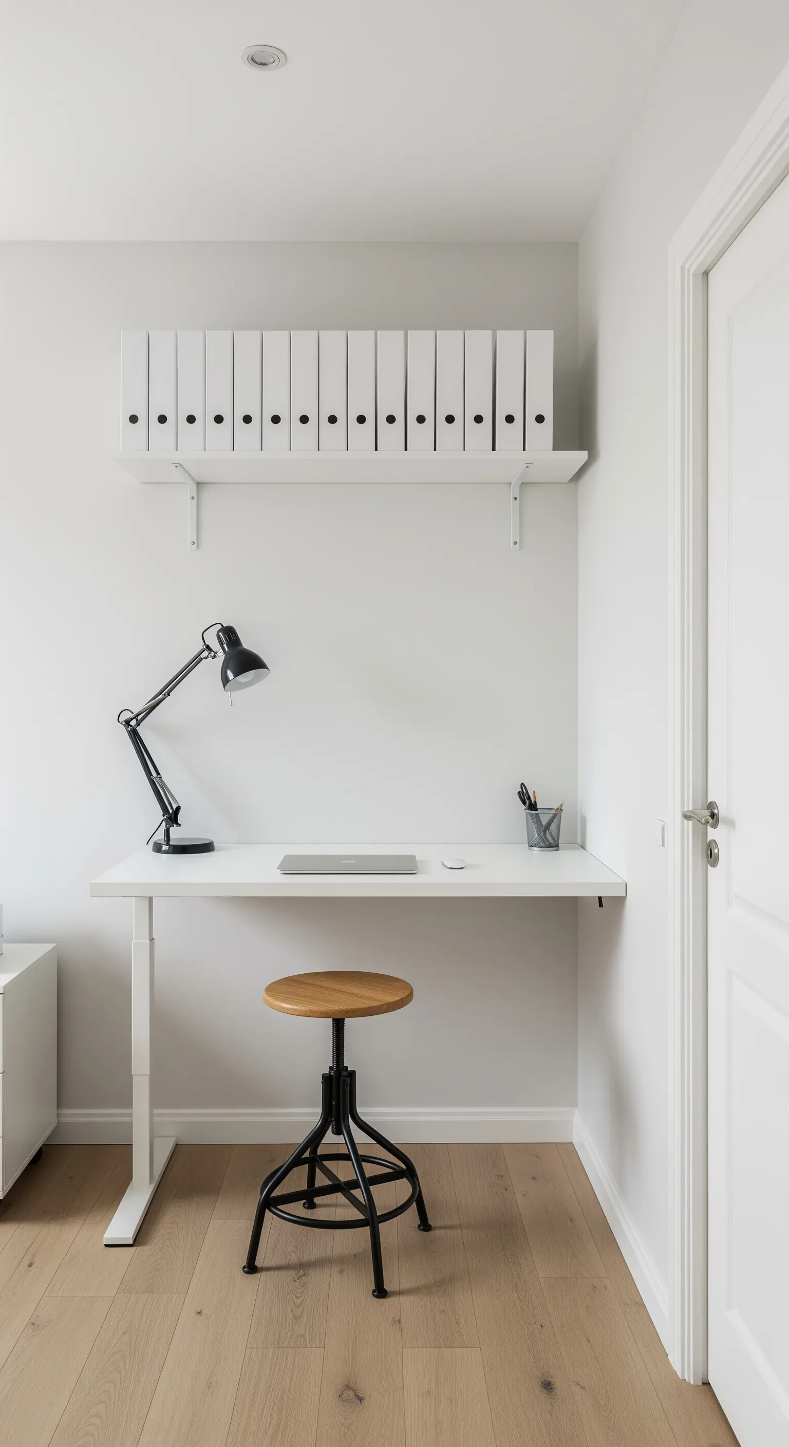 Kompakter weißer Schreibtisch mit einem Regal darüber, auf dem weiße Ordner stehen.