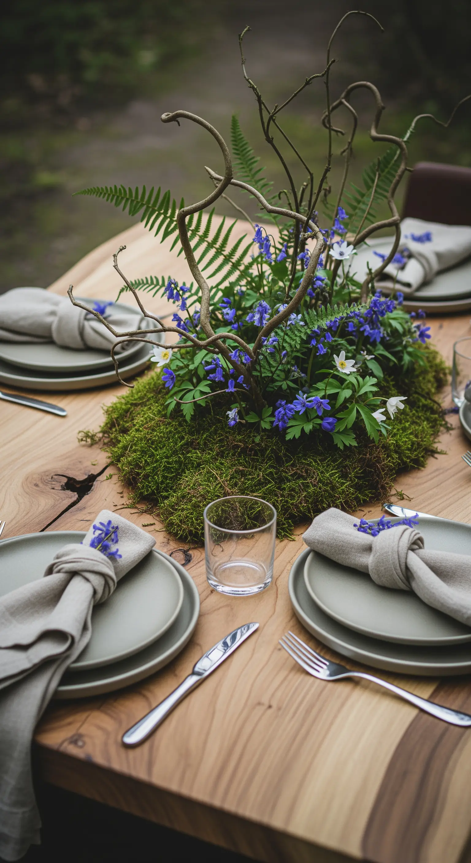 Natürliche Tischdeko mit Moos, Farn, Zweigen und blauen Waldblumen