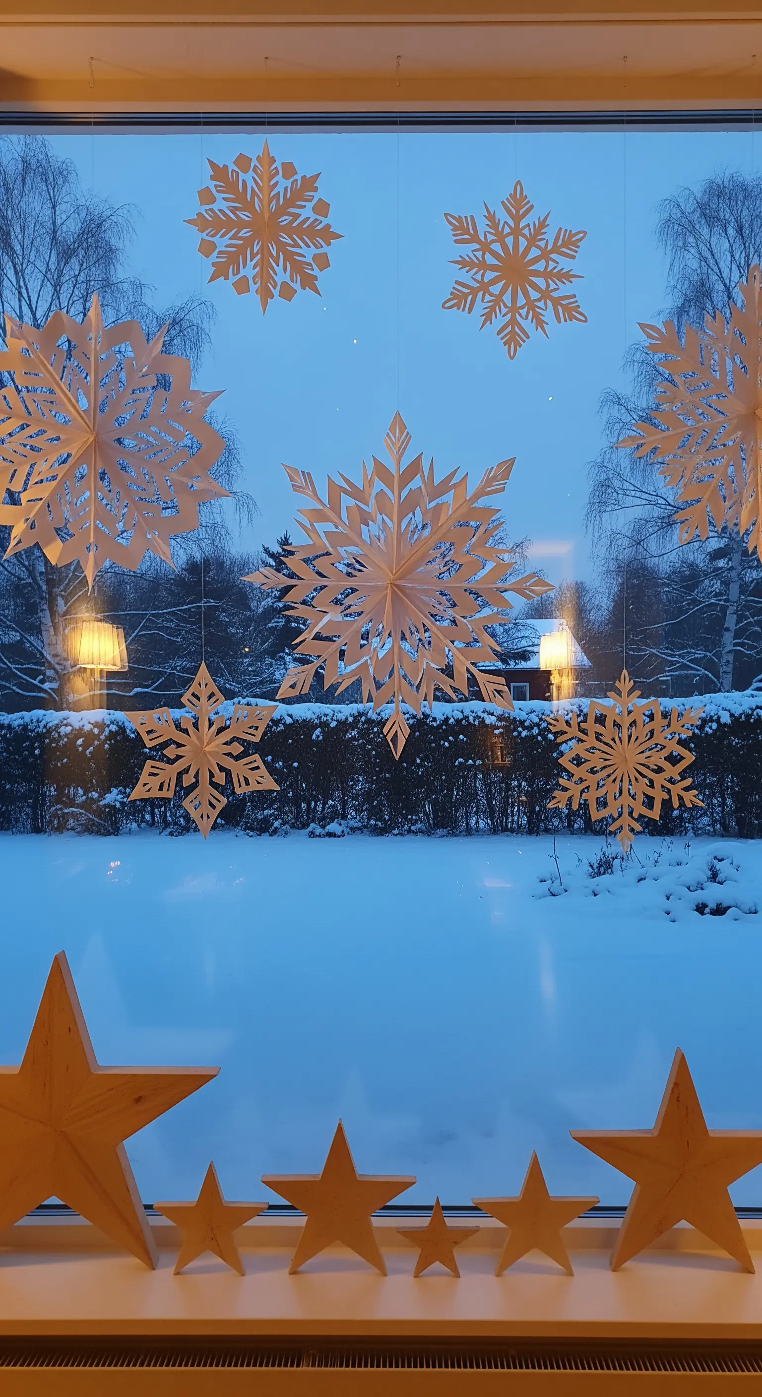 Fenster mit großen Papier-Schneeflocken und Holzsternen