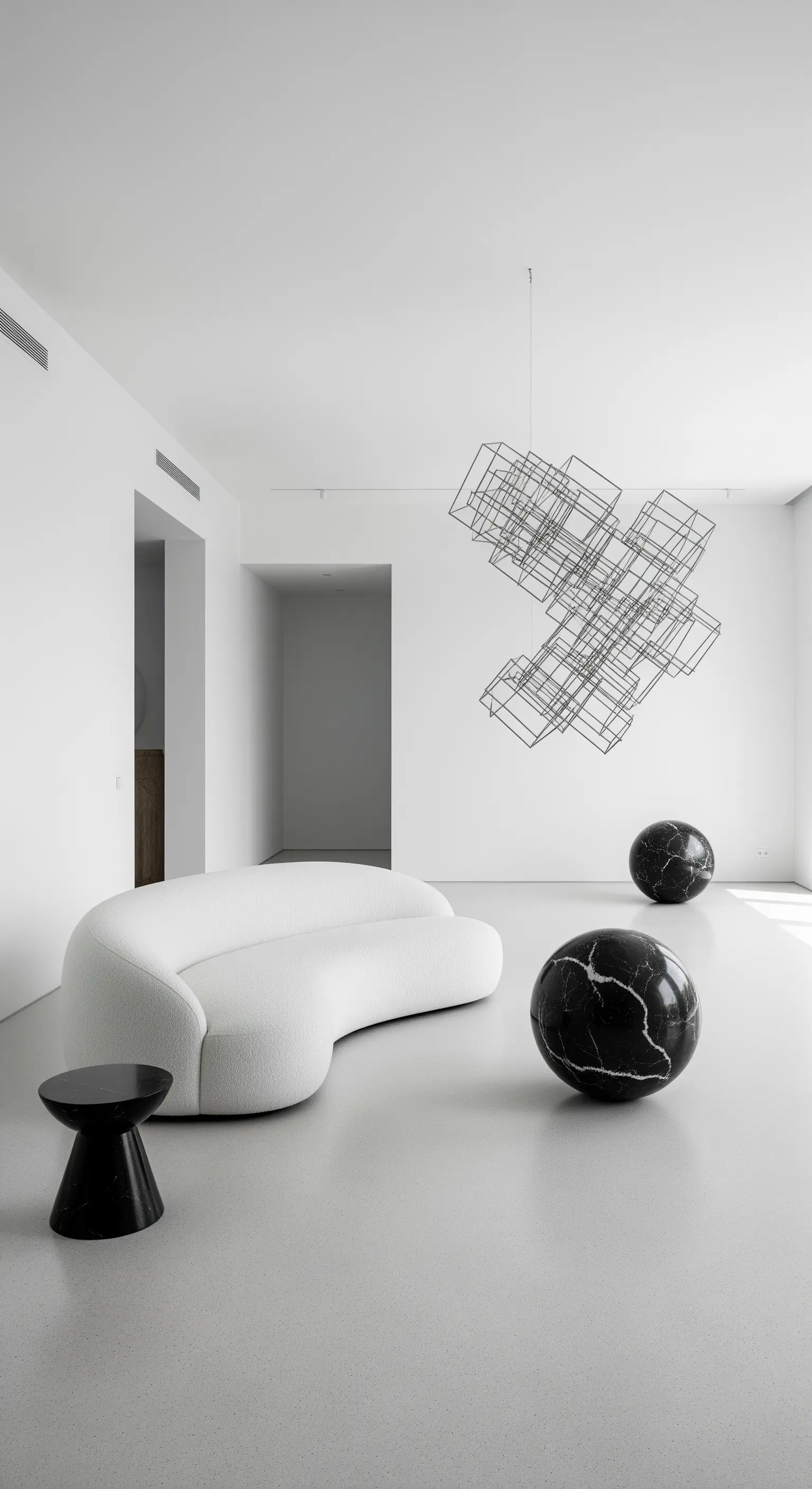 Minimalistisches weißes Wohnzimmer mit einer geschwungenen weißen Couch und schwarzen Marmorkugeln als Kunst.