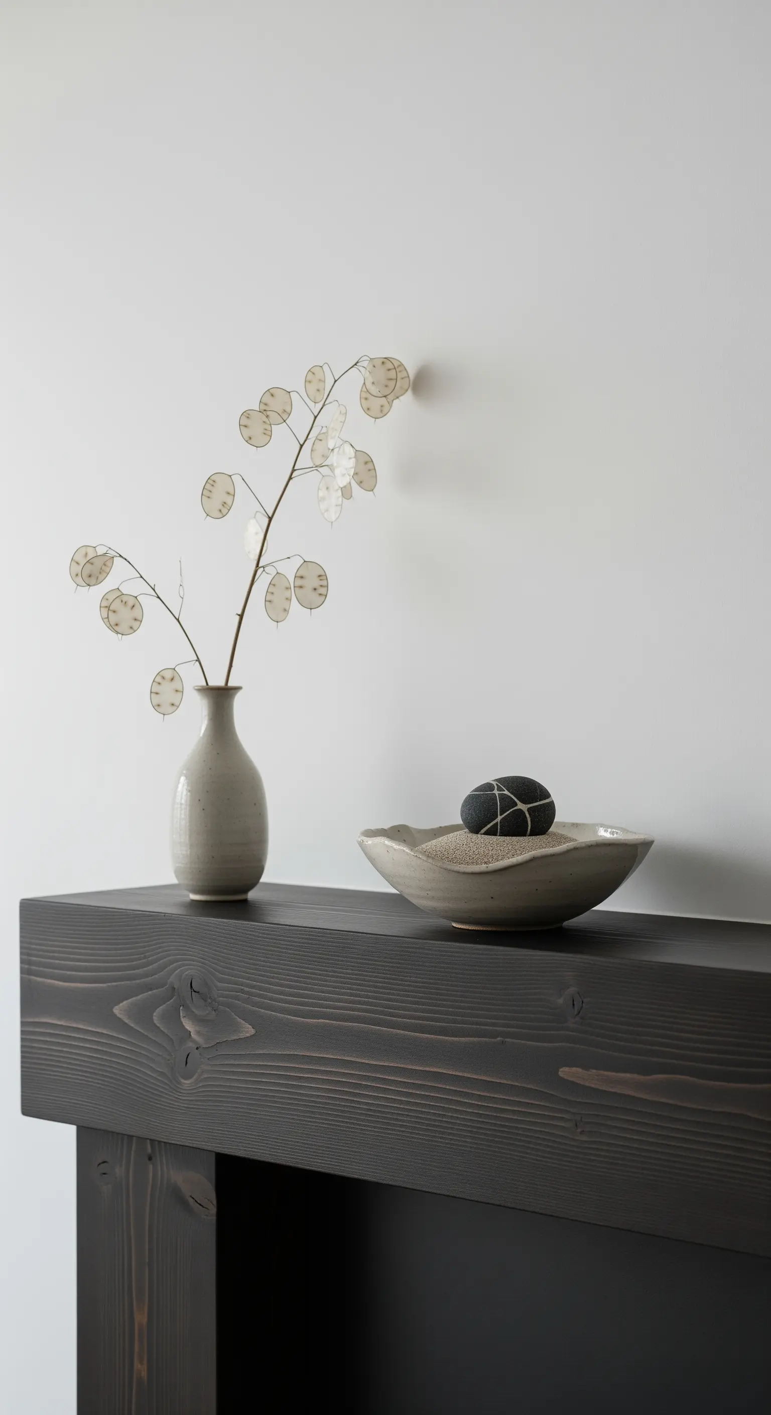 Minimalistische Zen-Deko mit Sand, Stein und Silberblatt auf dunklem Holz.